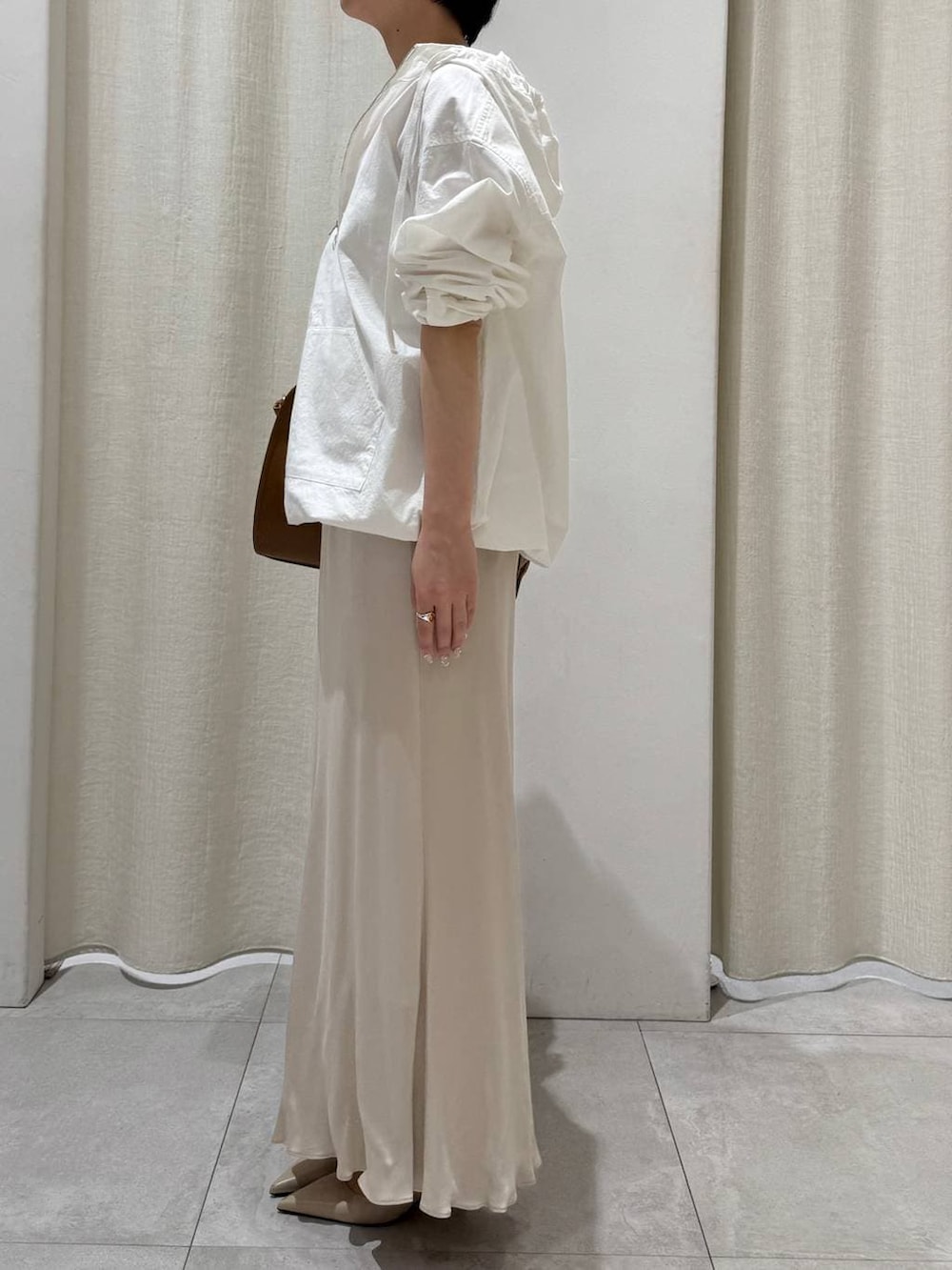 ホワイト系のパーカー、ベージュ系のスカート、ブラウン系のボストンバッグを着用したレディースの冬コーディネートの2枚目の写真