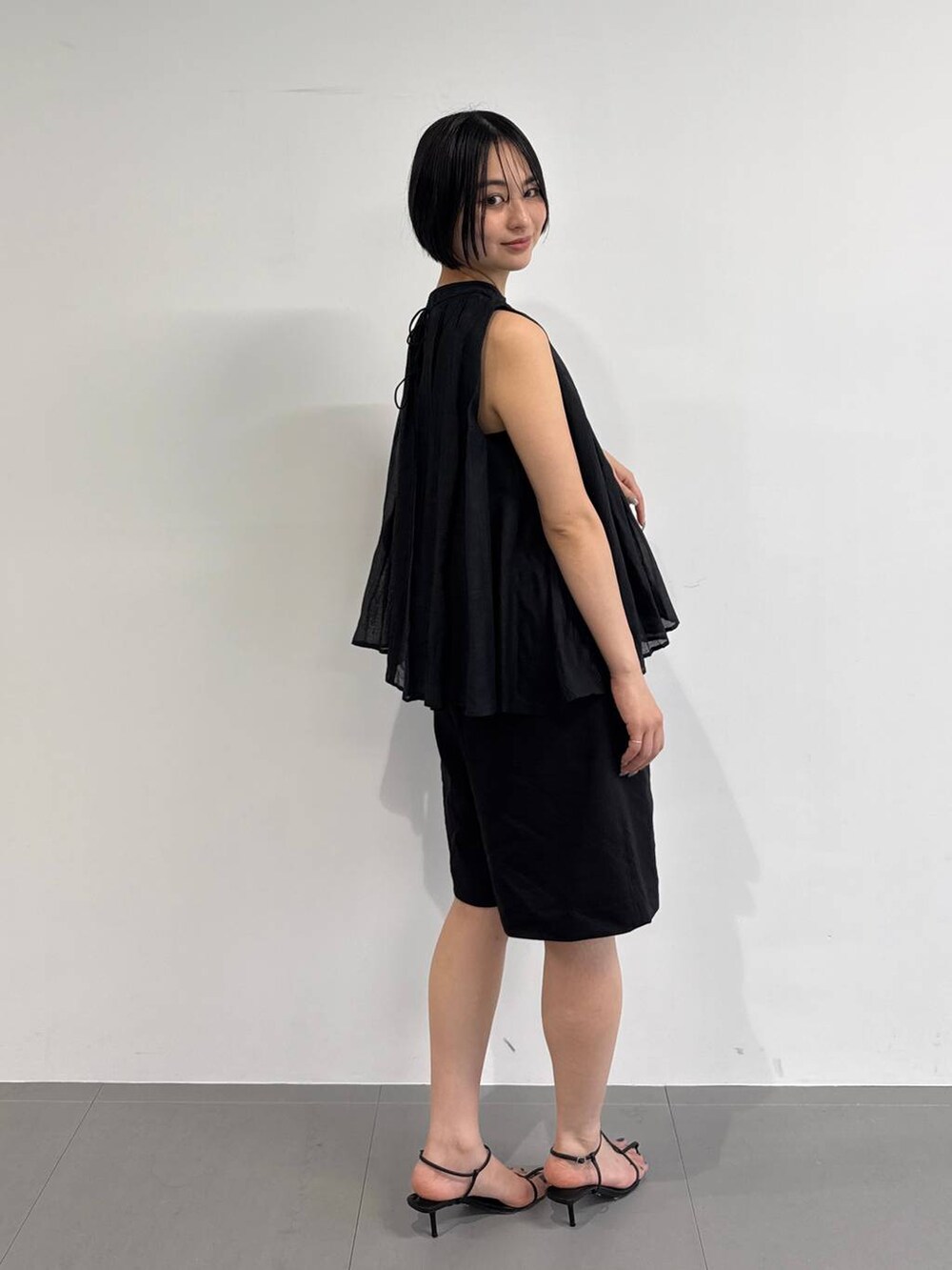 レッド系のショルダーバッグ、ブラック系のサンダル、ブラック系のシャツ/ブラウスを着用したレディースの夏コーディネートの2枚目の写真