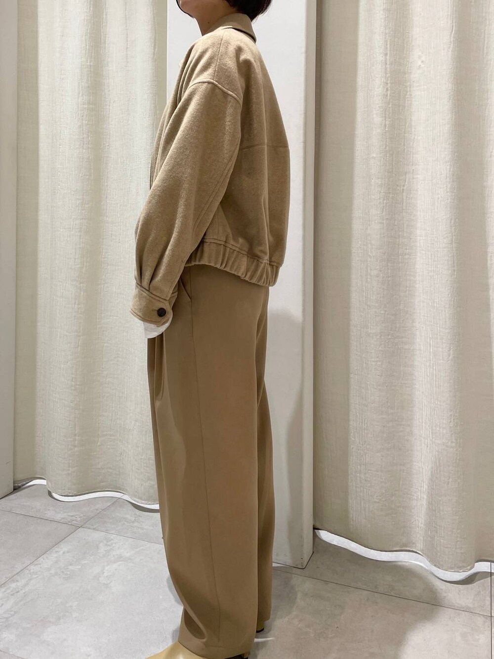 ホワイト系のハンドバッグ、ホワイト系のニット/セーター、ベージュ系のブルゾンを着用したレディースの秋コーディネートの2枚目の写真