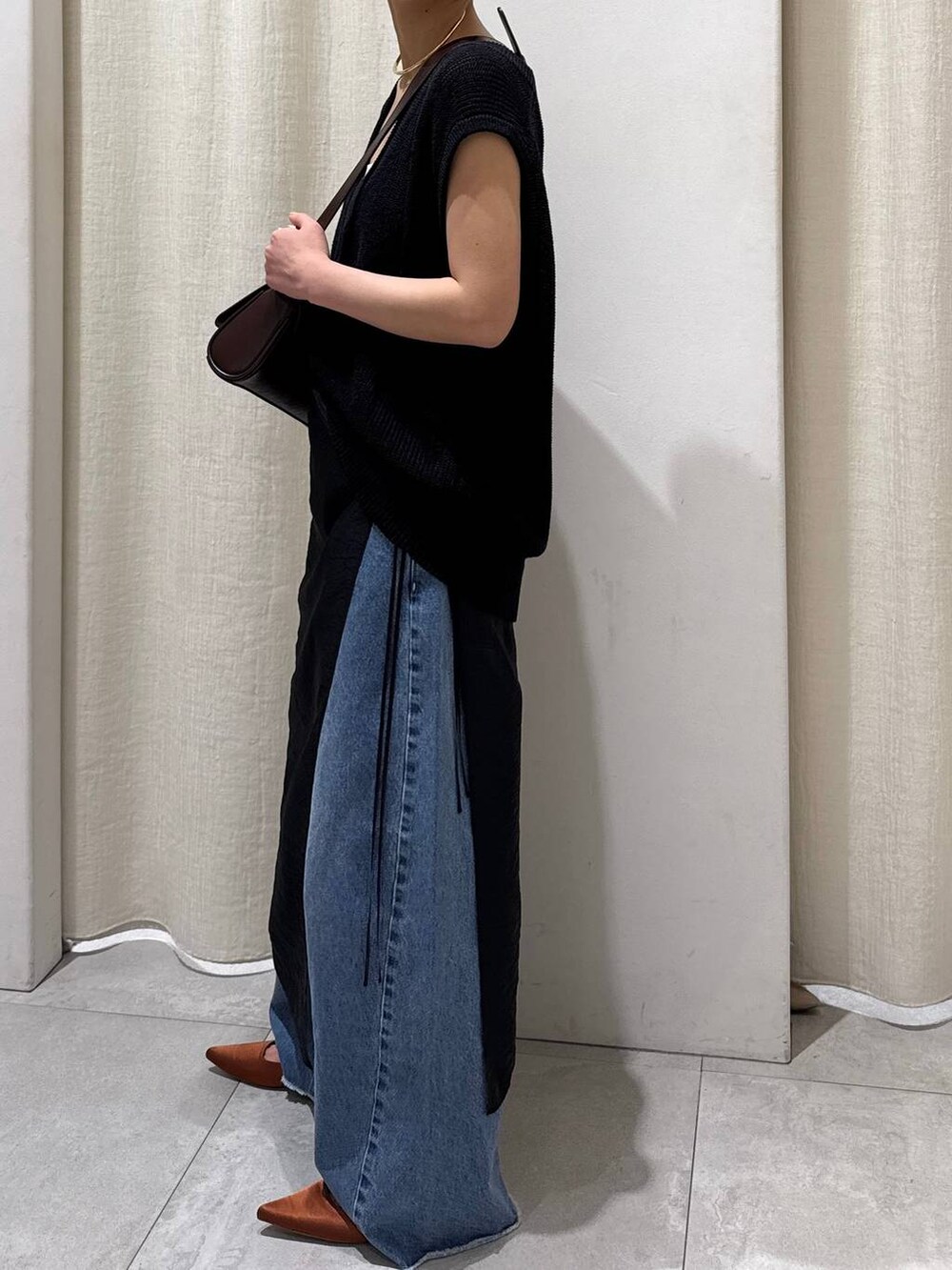 ブラック系のスカート、ブルー系のデニムパンツ、ブラウン系のパンプスを着用したレディースの春コーディネートの4枚目の写真