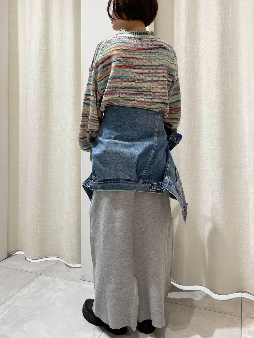 ブラック系のブーツ、ブルー系のデニムジャケット、グレー系のスカートを着用したレディースの秋コーディネートの2枚目の写真