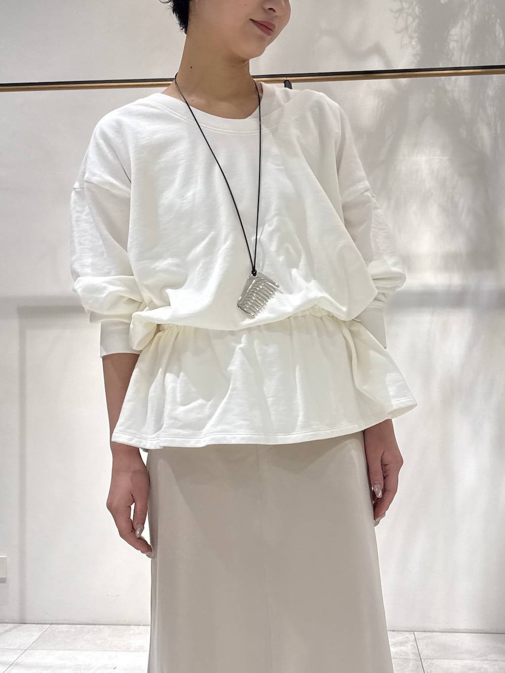 ベージュ系のスカート、ベージュ系のスニーカー、ホワイト系のスウェットを着用したレディースの春コーディネートの4枚目の写真