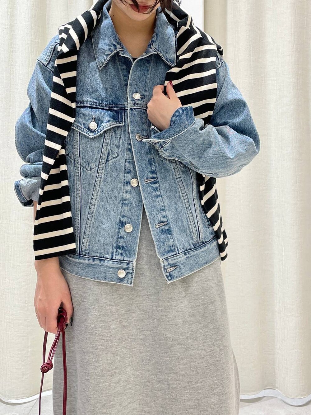 ブルー系のデニムジャケット、レッド系のショルダーバッグ、ブラック系のTシャツ/カットソーを着用したレディースの秋コーディネートの2枚目の写真