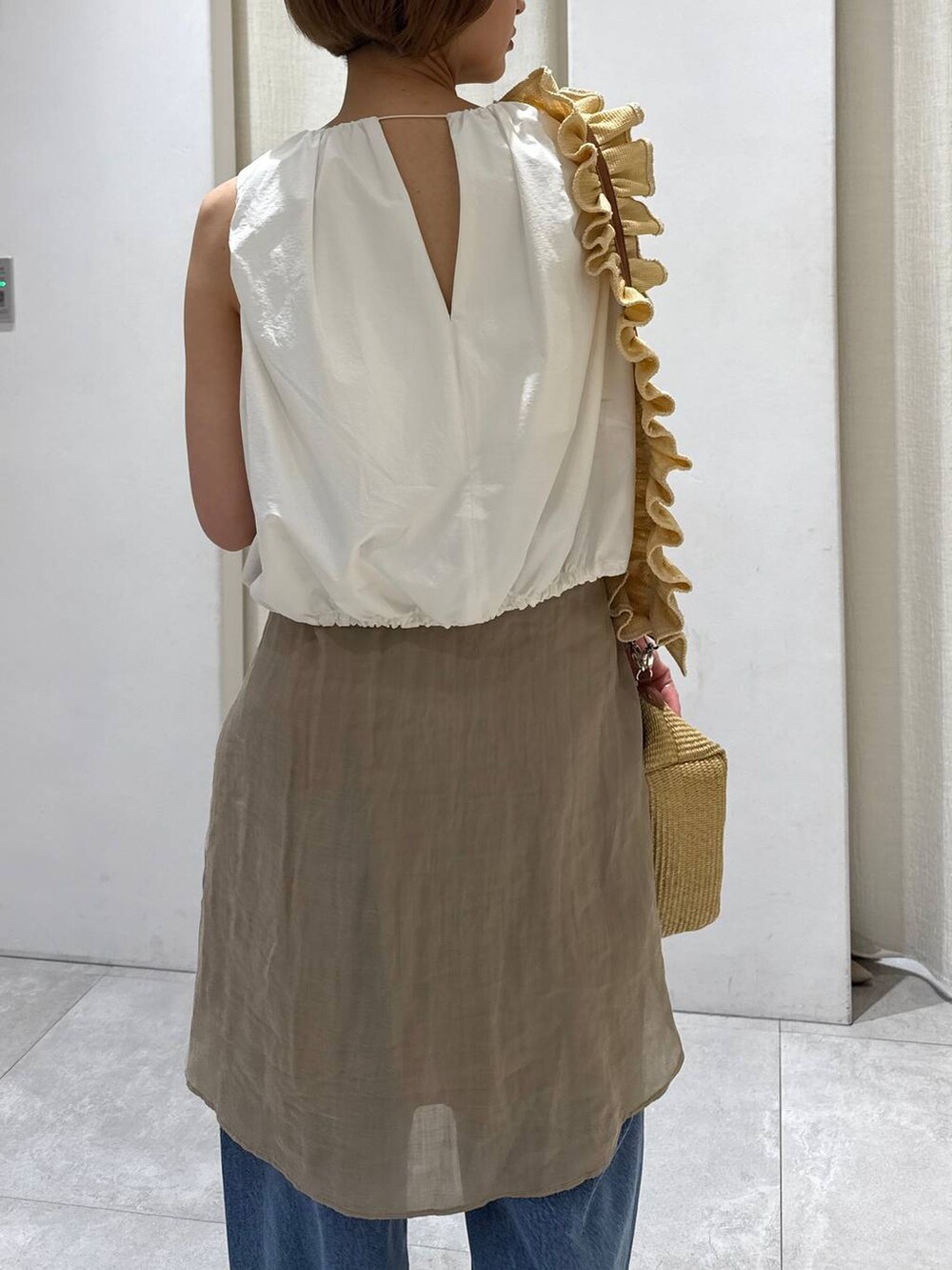 ベージュ系のショルダーバッグ、ブルー系のデニムパンツ、ベージュ系のシャツ/ブラウスを着用したレディースの春コーディネートの2枚目の写真