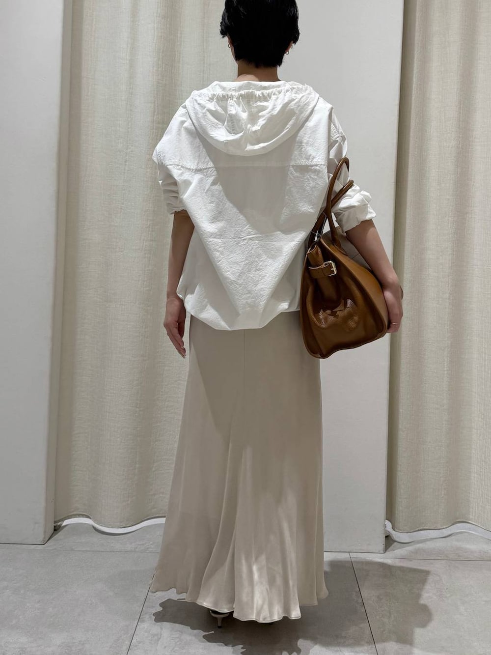 ホワイト系のパーカー、ベージュ系のスカート、ブラウン系のボストンバッグを着用したレディースの冬コーディネートの3枚目の写真