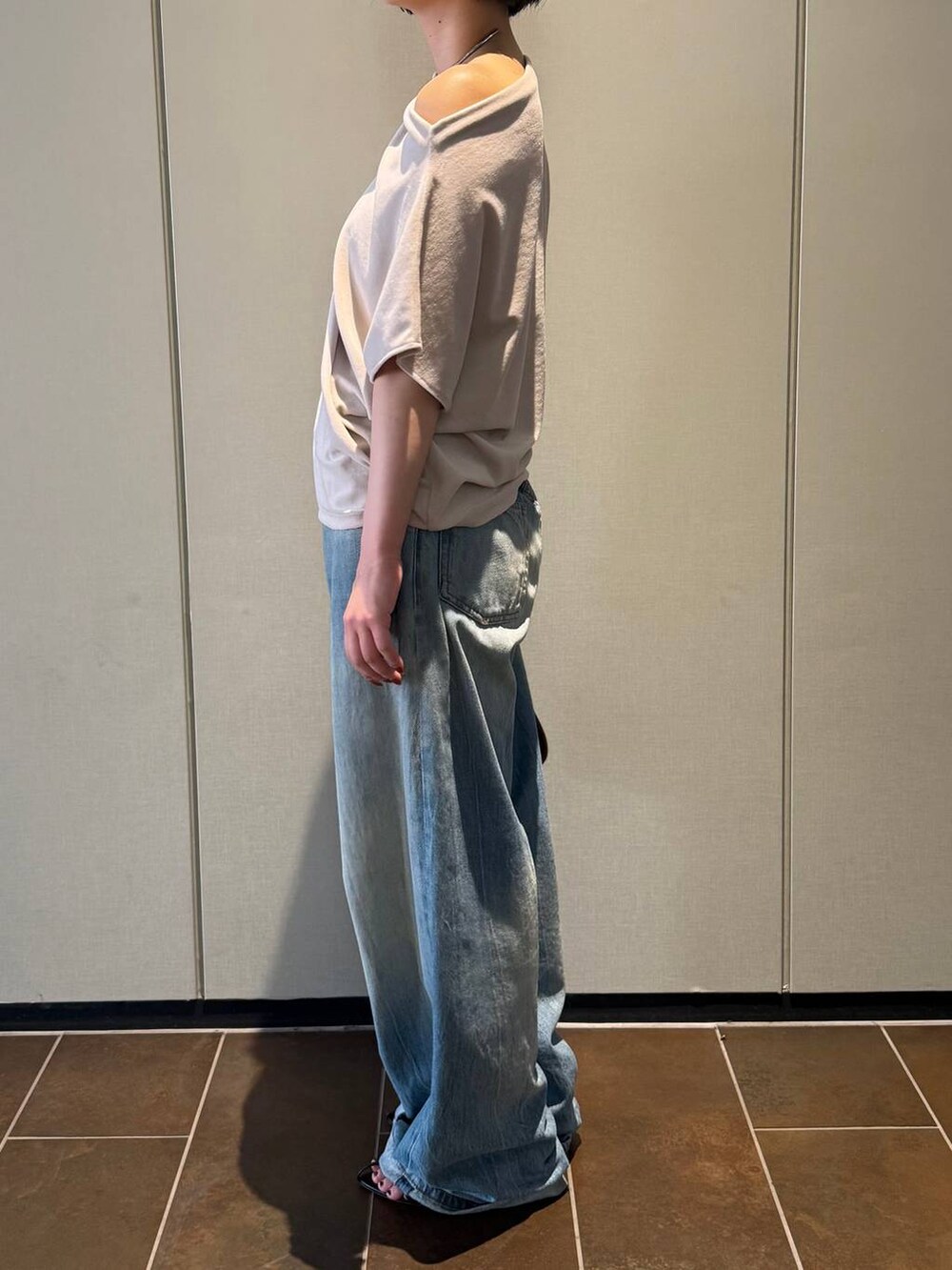 ブラック系のサンダル、ベージュ系のTシャツ/カットソー、ブルー系のデニムパンツを着用したレディースの夏コーディネートの2枚目の写真