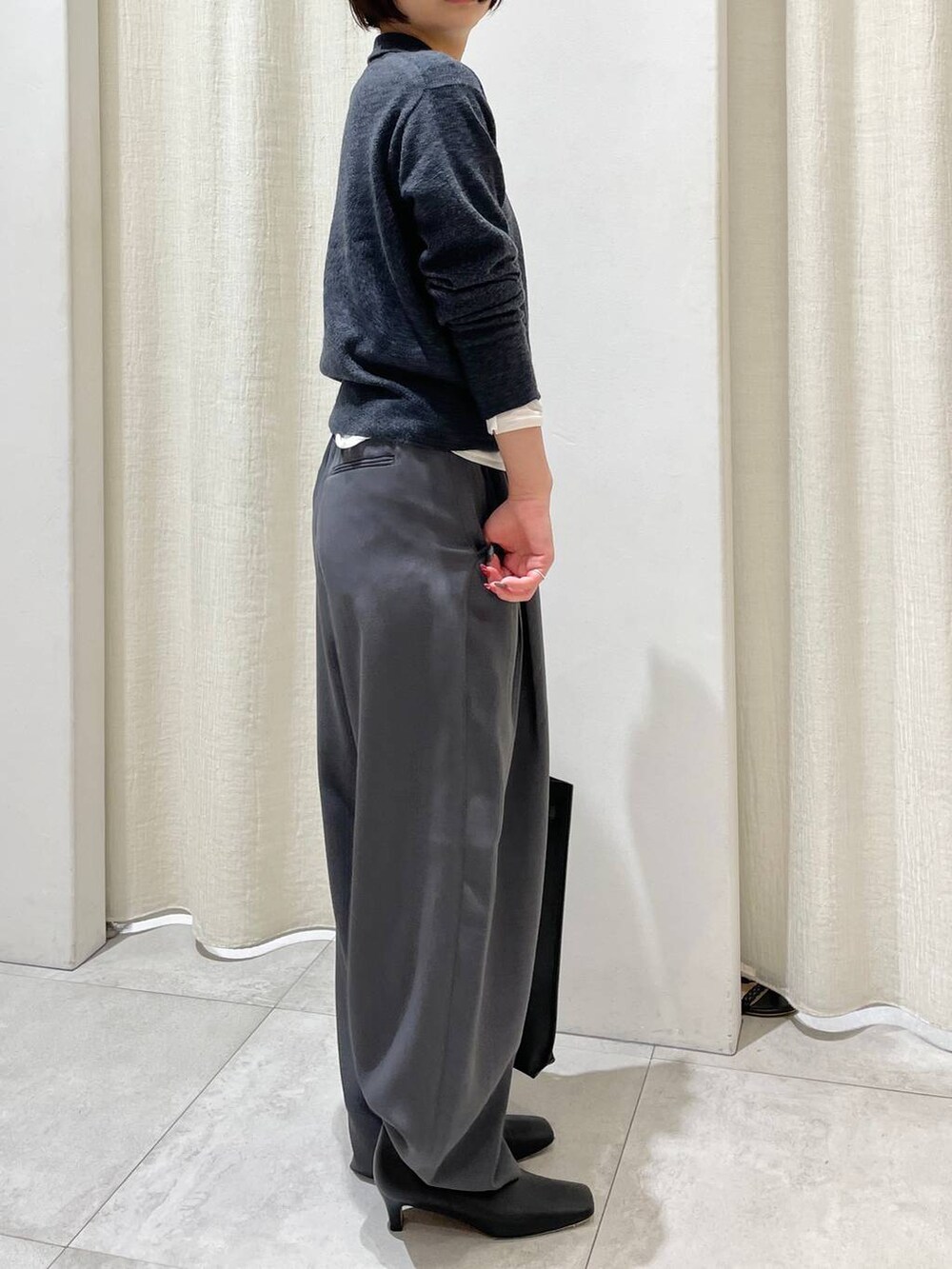 ブラック系のトートバッグ、ホワイト系のTシャツ/カットソー、グレー系のニット/セーターを着用したレディースの秋コーディネートの3枚目の写真