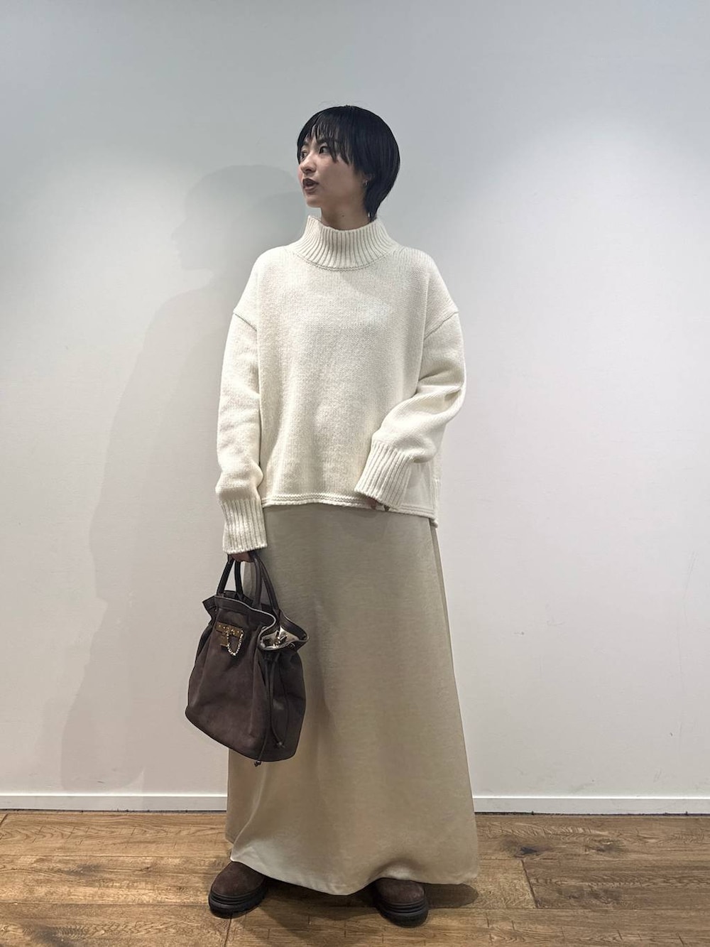 ホワイト系のニット/セーター、ブラウン系のブーツ、ブラウン系のトートバッグを着用したレディースの秋コーディネートの4枚目の写真