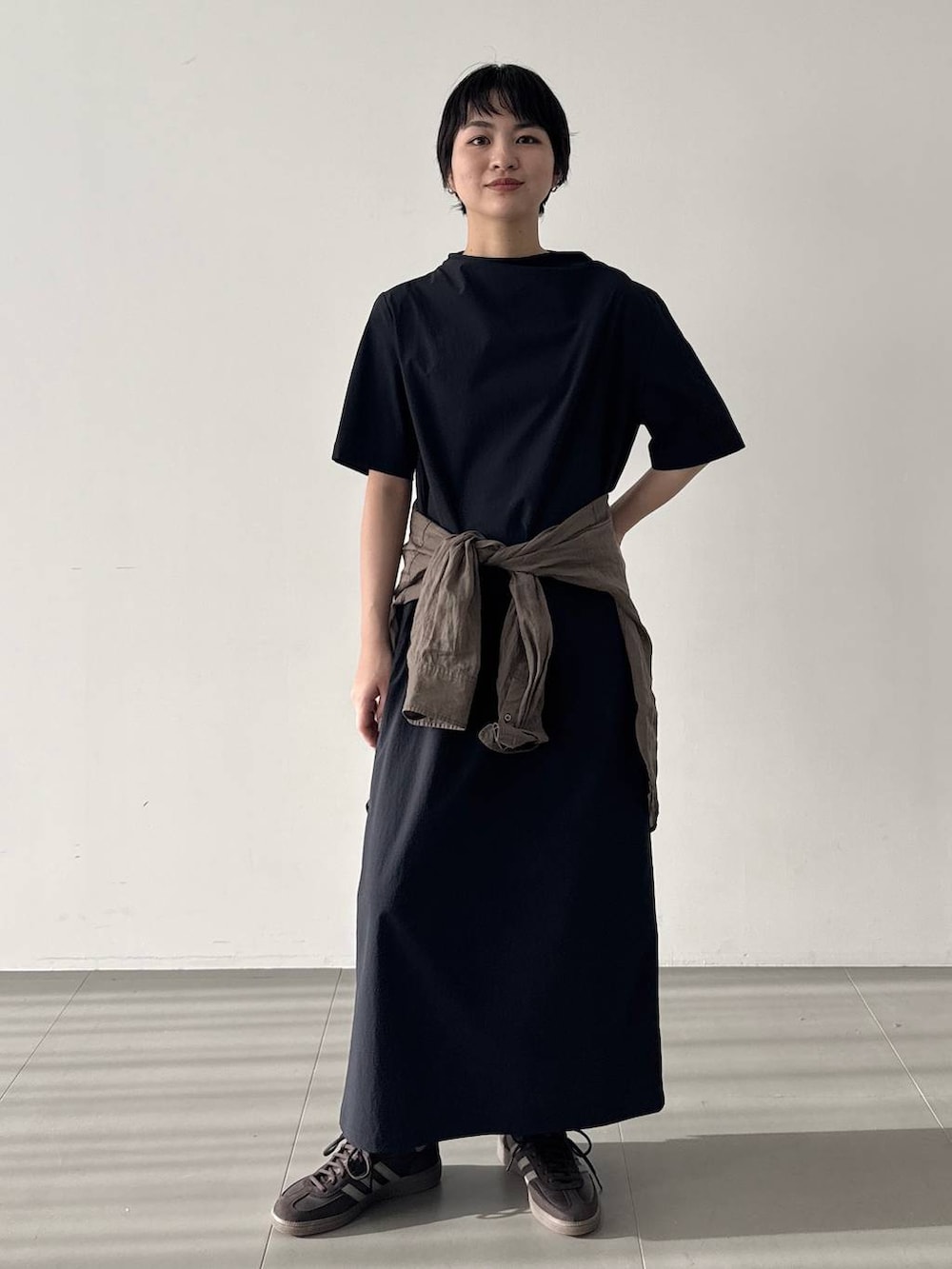 ブラウン系のスニーカー、ブラック系のワンピース、グリーン系のシャツ/ブラウスを着用したレディースの春コーディネートの2枚目の写真