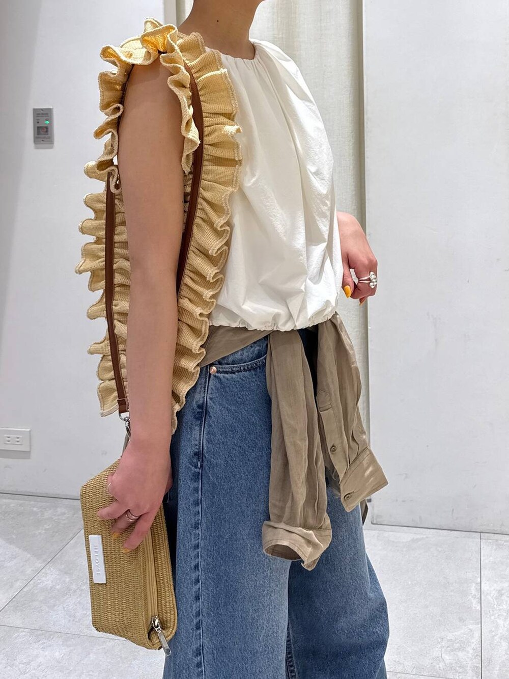 ベージュ系のショルダーバッグ、ブルー系のデニムパンツ、ベージュ系のシャツ/ブラウスを着用したレディースの春コーディネートの3枚目の写真