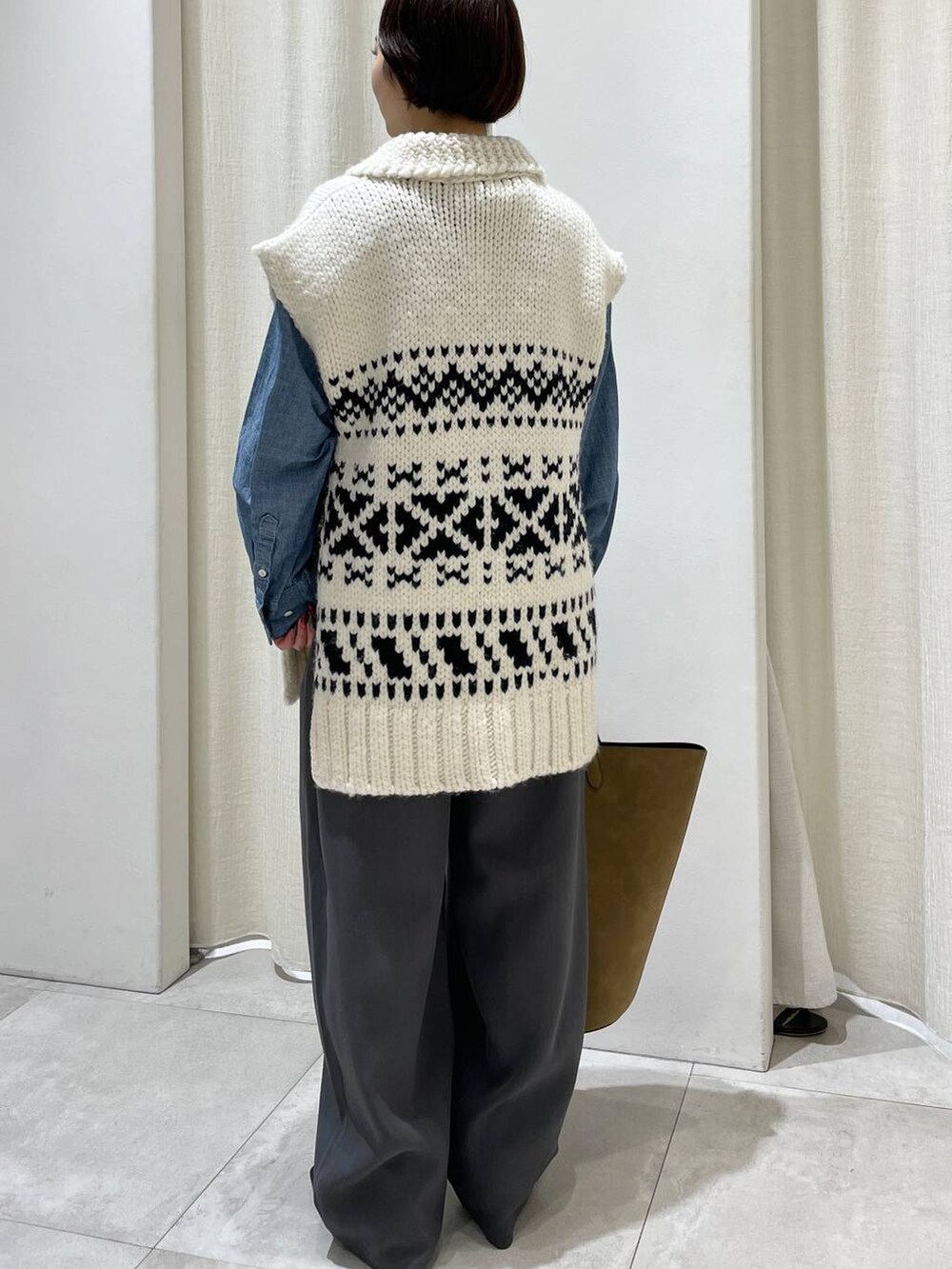 ブラウン系のトートバッグ、ブルー系のシャツ/ブラウス、ホワイト系のベストを着用したレディースの秋コーディネートの3枚目の写真