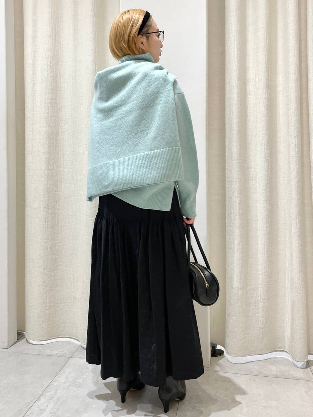 グリーン系のニット/セーター、グリーン系のニット/セーター、ブラック系のスカートを着用したレディースの冬コーディネートの3枚目の写真