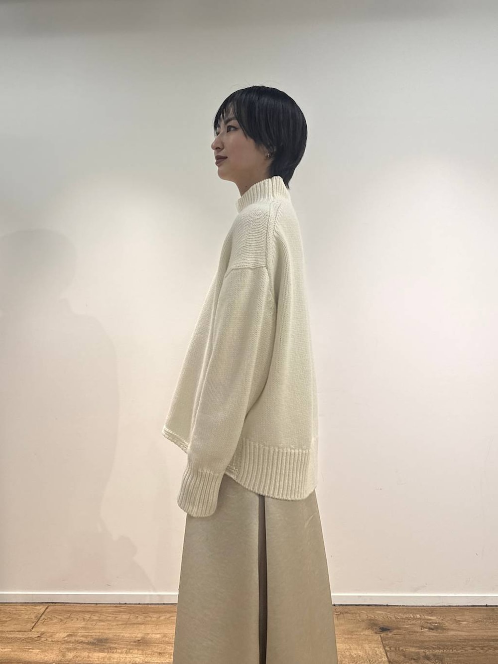 ホワイト系のニット/セーター、ブラウン系のブーツ、ブラウン系のトートバッグを着用したレディースの秋コーディネートの3枚目の写真