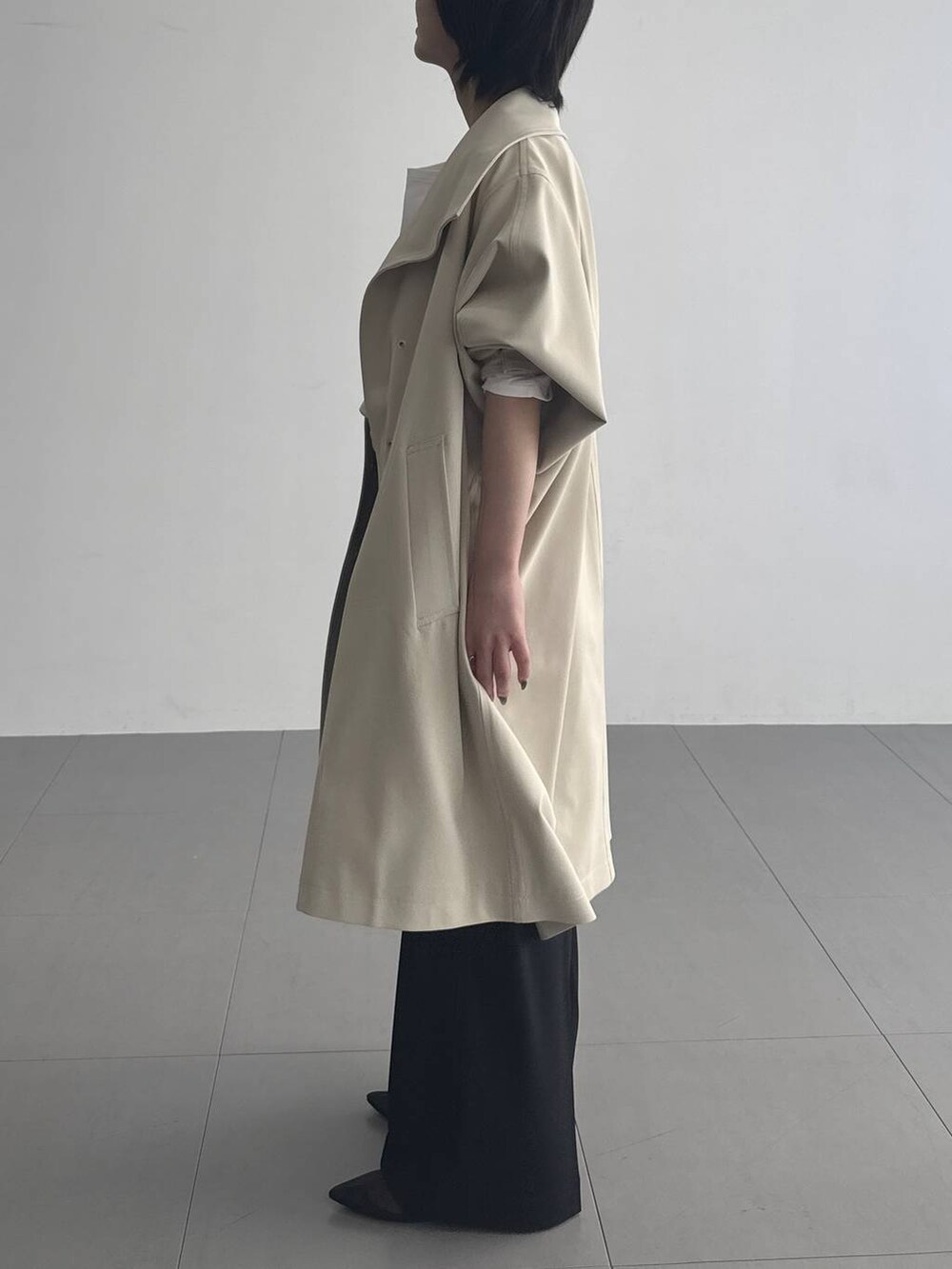 ベージュ系のその他アウター、ブラック系のスラックス、ブラック系のネックレスを着用したレディースの冬コーディネートの2枚目の写真