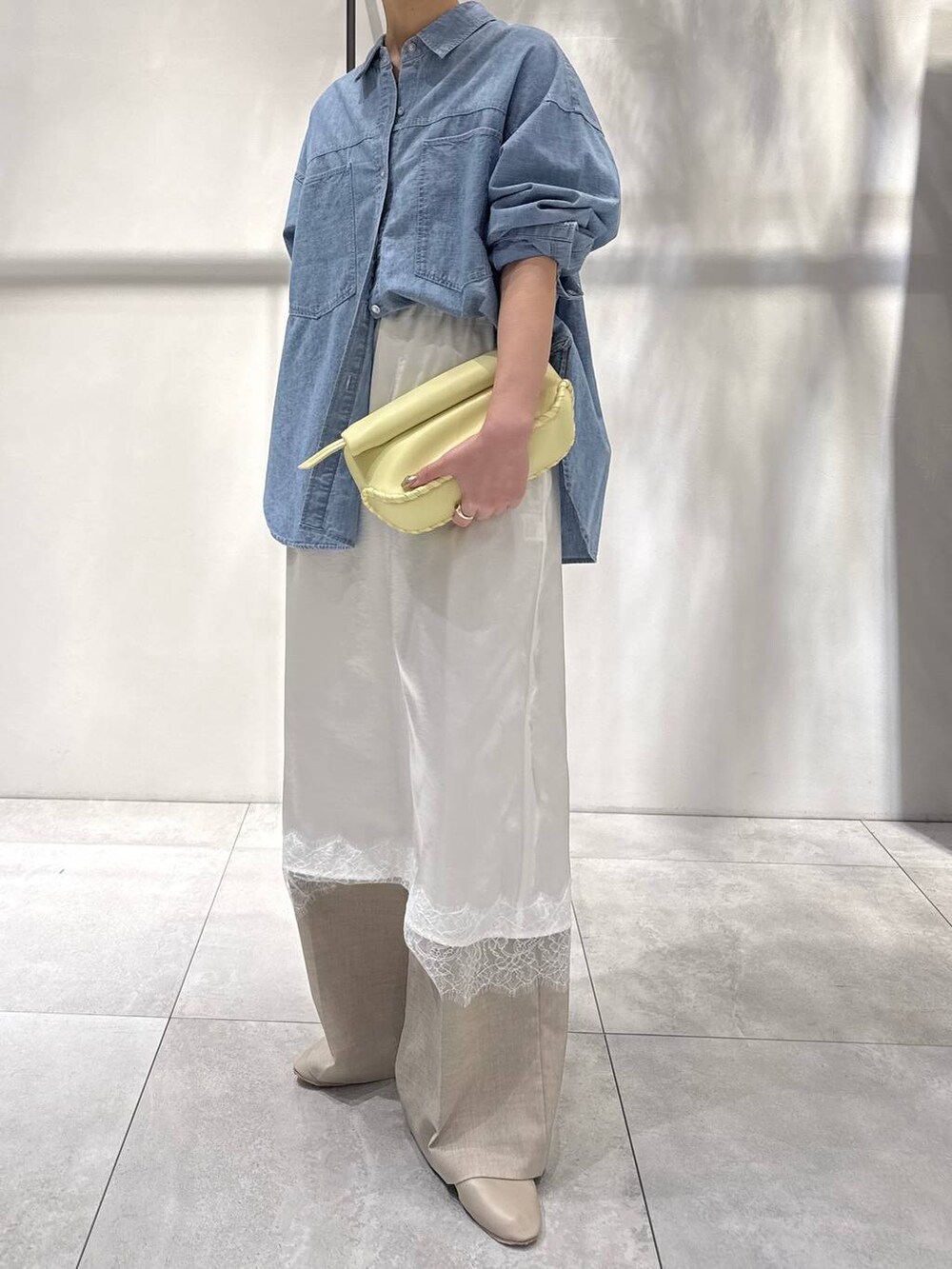 ブルー系のシャツ/ブラウス、イエロー系のハンドバッグ、ベージュ系のパンプスを着用したレディースの春コーディネートの2枚目の写真