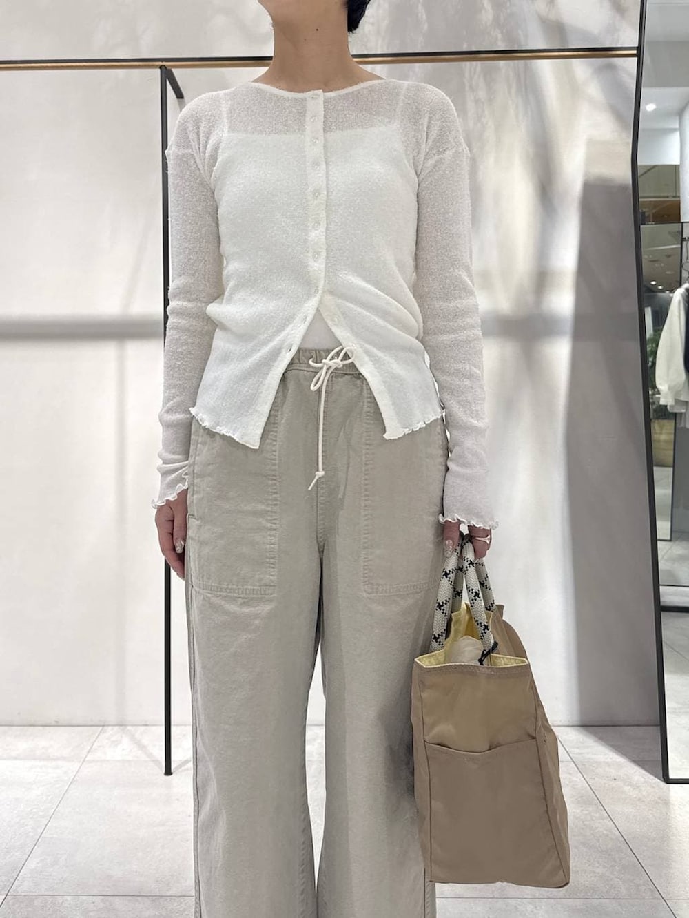 ベージュ系のその他パンツ、ベージュ系のトートバッグ、ホワイト系のカーディガン/ボレロを着用したレディースの冬コーディネートの3枚目の写真