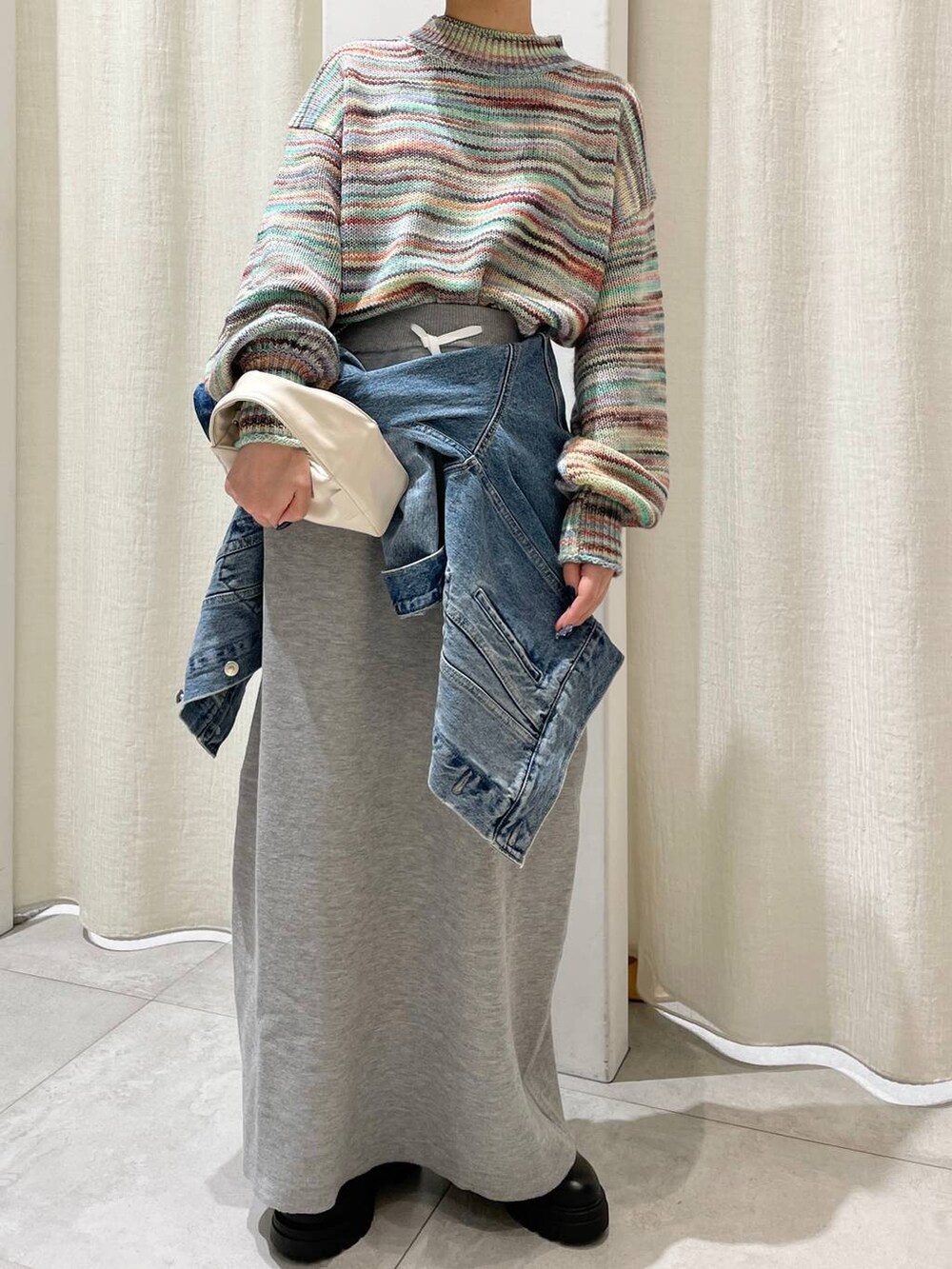 ブラック系のブーツ、ブルー系のデニムジャケット、グレー系のスカートを着用したレディースの秋コーディネートの3枚目の写真