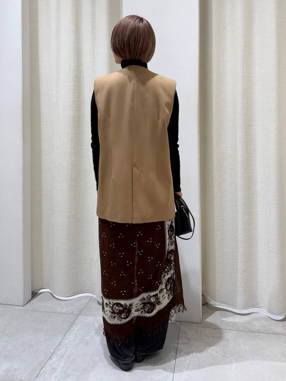 ブラック系のデニムパンツ、ベージュ系のその他アウター、ブラック系のショルダーバッグを着用したレディースの冬コーディネートの3枚目の写真