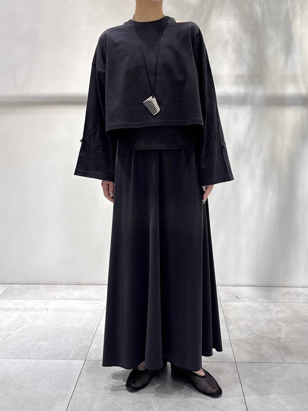 ブラック系のパンプス、グレー系のアンサンブル、グレー系のスカートを着用したレディースの春コーディネートの5枚目の写真