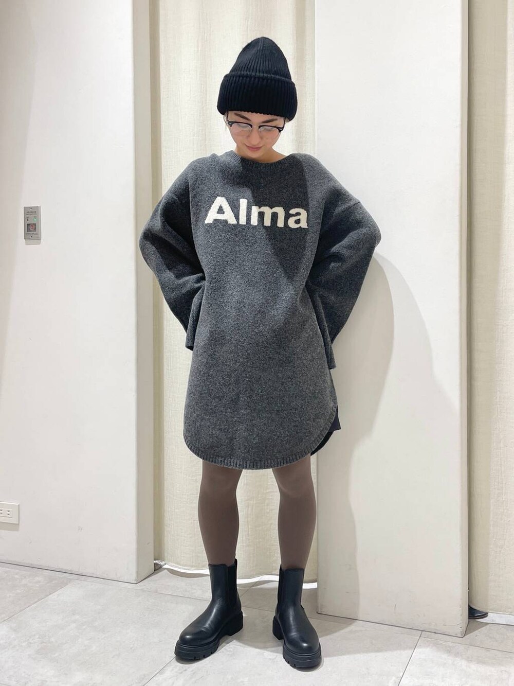 ブラック系のブーツ、グレー系のワンピース、ブラック系のニットキャップ/ビーニーを着用したレディースの冬コーディネートの2枚目の写真