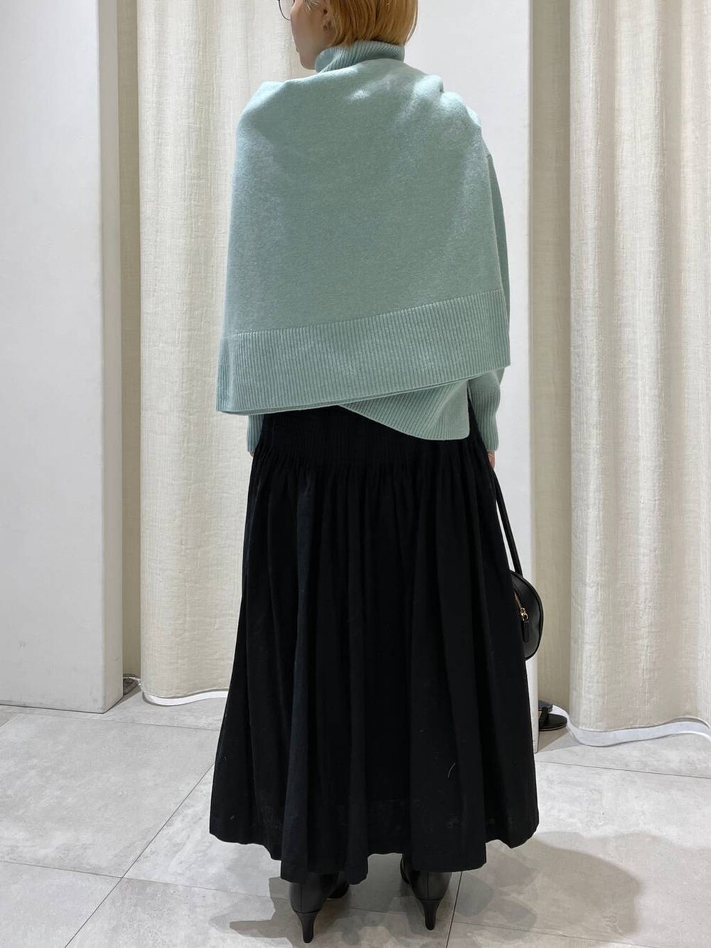 グリーン系のニット/セーター、グリーン系のニット/セーター、ブラック系のスカートを着用したレディースの冬コーディネートの5枚目の写真