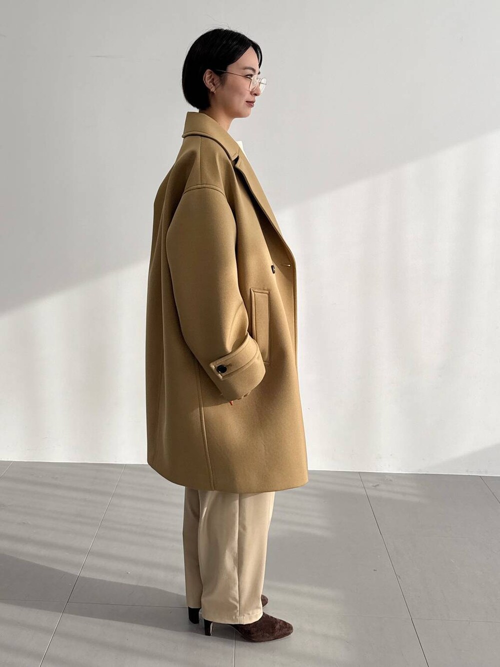 ベージュ系のその他パンツ、ベージュ系のピーコート、ブラウン系のブーツを着用したレディースの秋コーディネートの3枚目の写真