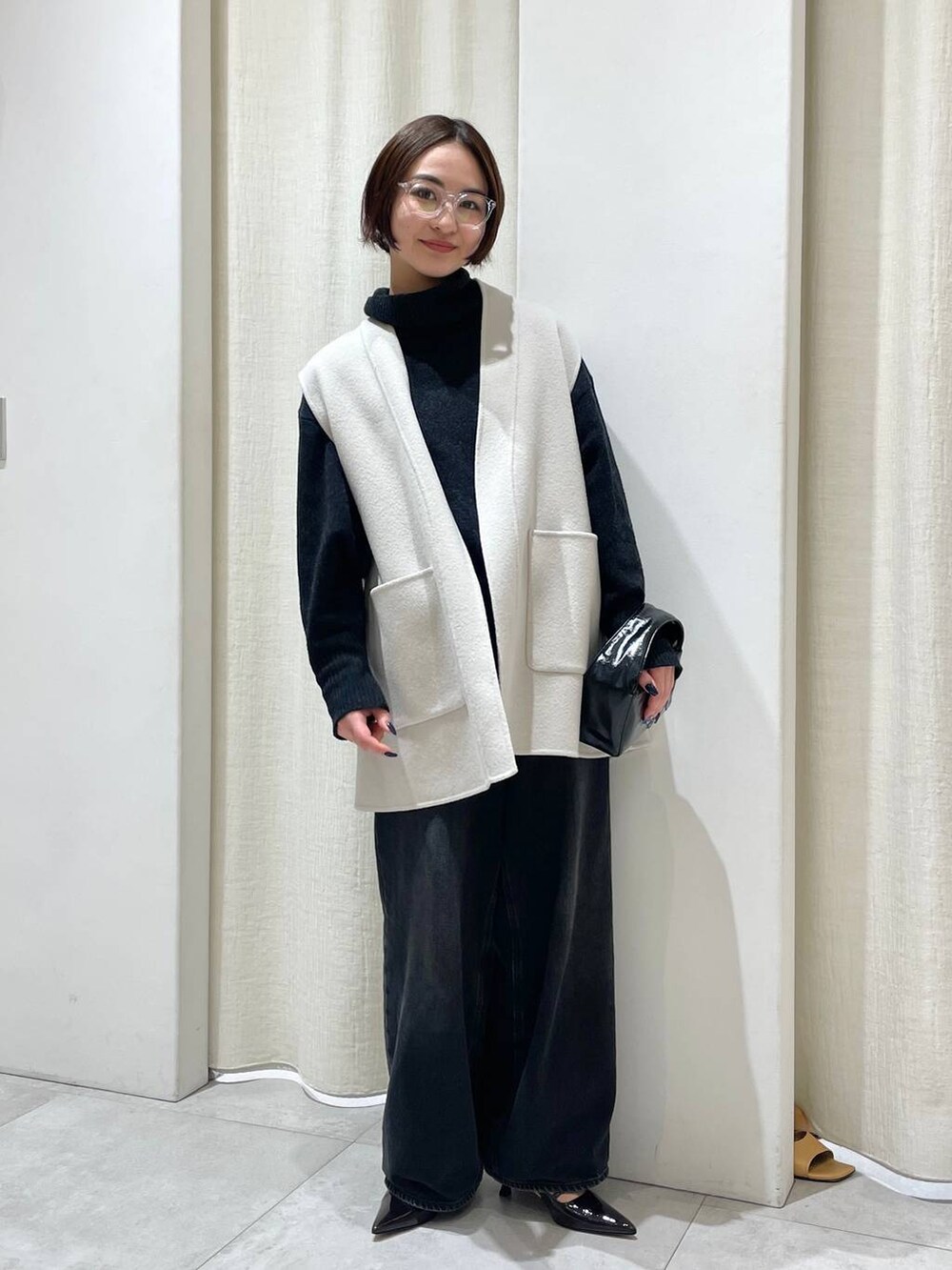 ブラック系のデニムパンツ、ホワイト系のその他アウター、グレー系のニット/セーターを着用したレディースの秋コーディネートの2枚目の写真