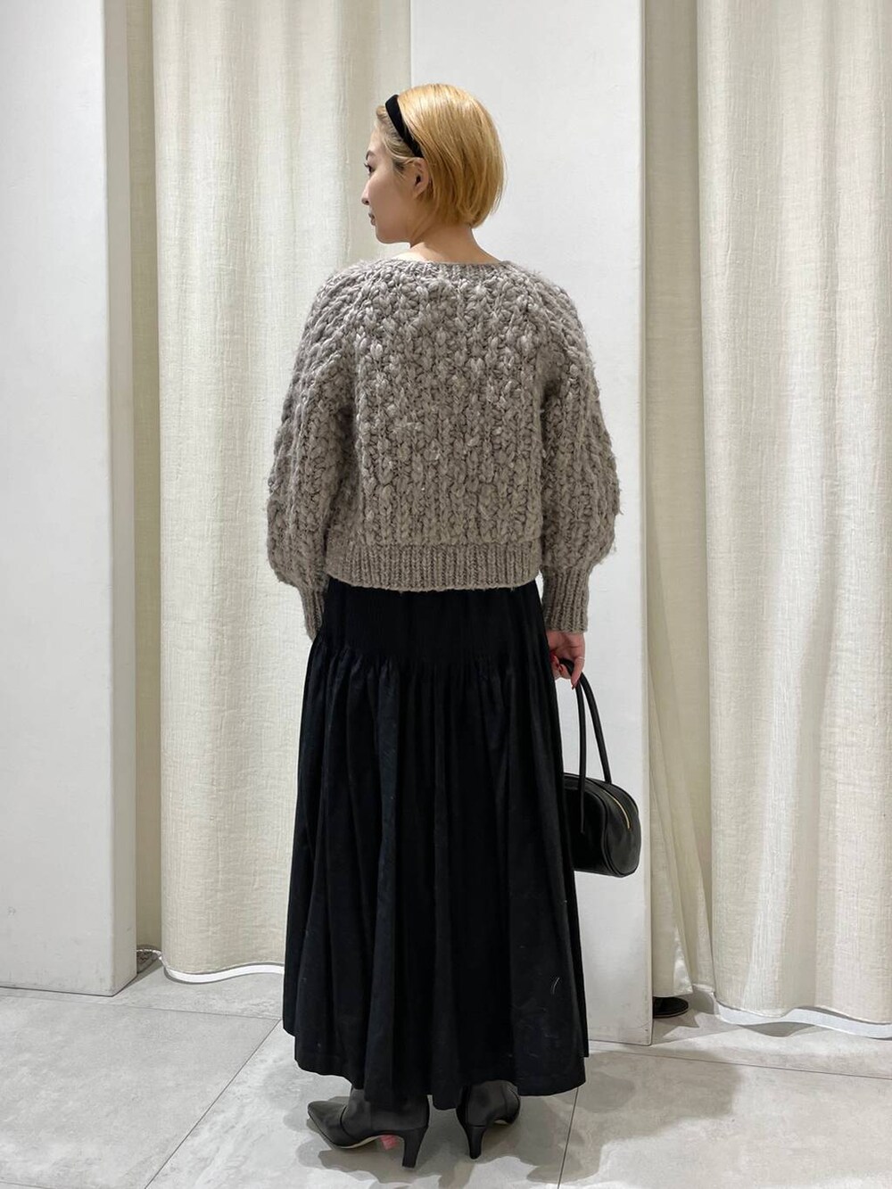 ベージュ系のカーディガン/ボレロ、ブラック系のスカートを着用したレディースの冬コーディネートの4枚目の写真