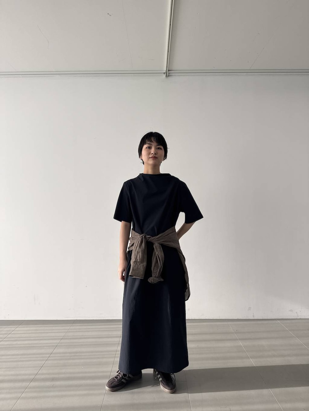 ブラウン系のスニーカー、ブラック系のワンピース、グリーン系のシャツ/ブラウスを着用したレディースの春コーディネートの4枚目の写真