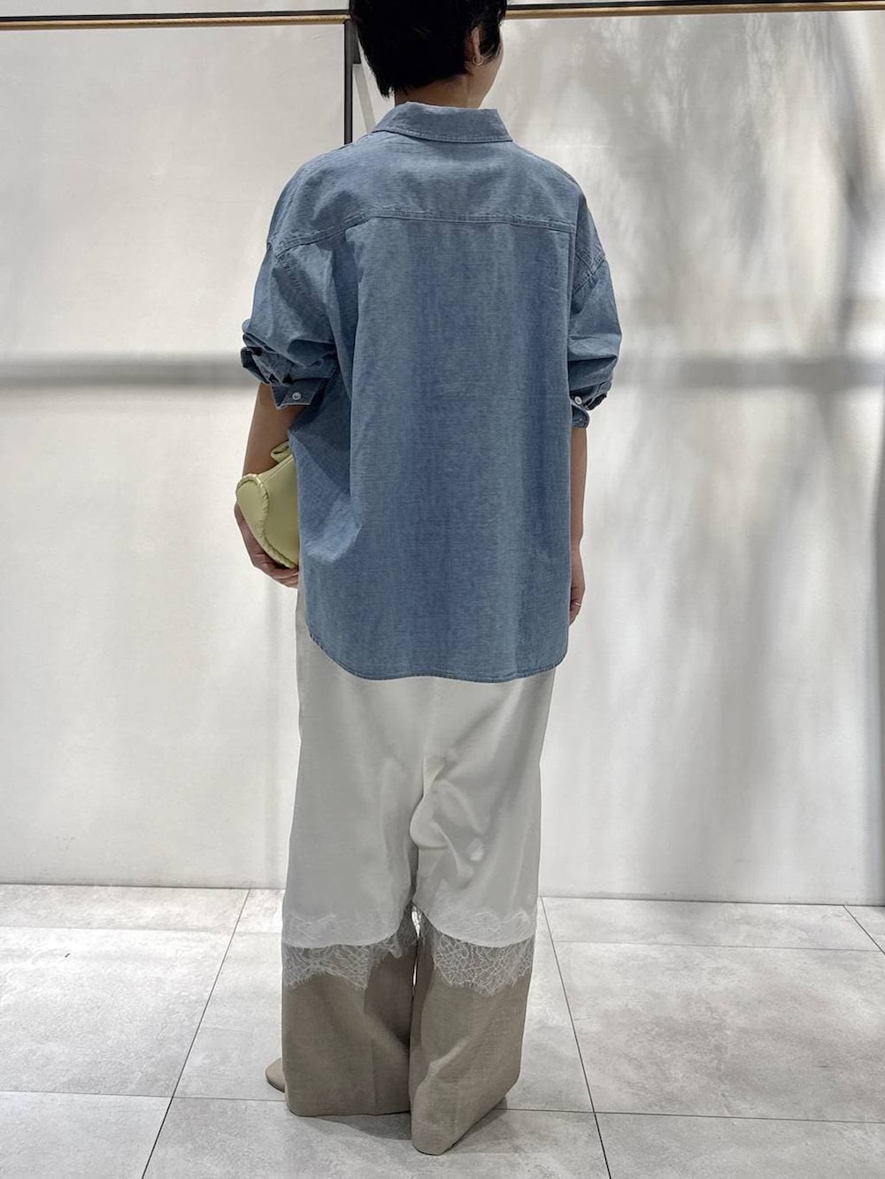 ブルー系のシャツ/ブラウス、イエロー系のハンドバッグ、ベージュ系のパンプスを着用したレディースの春コーディネートの4枚目の写真