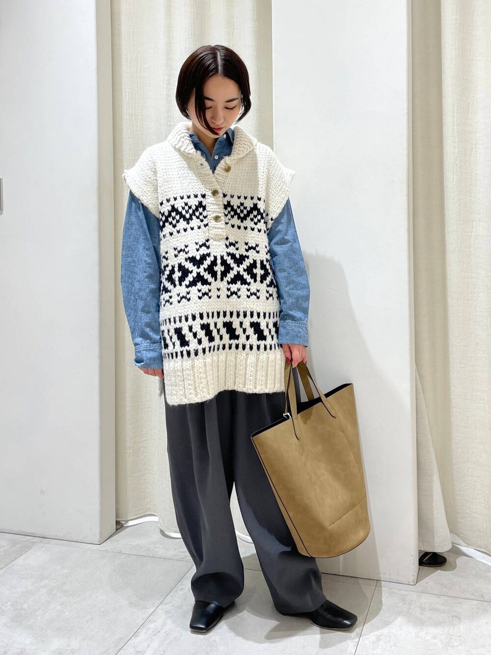 ブラウン系のトートバッグ、ブルー系のシャツ/ブラウス、ホワイト系のベストを着用したレディースの秋コーディネートの2枚目の写真