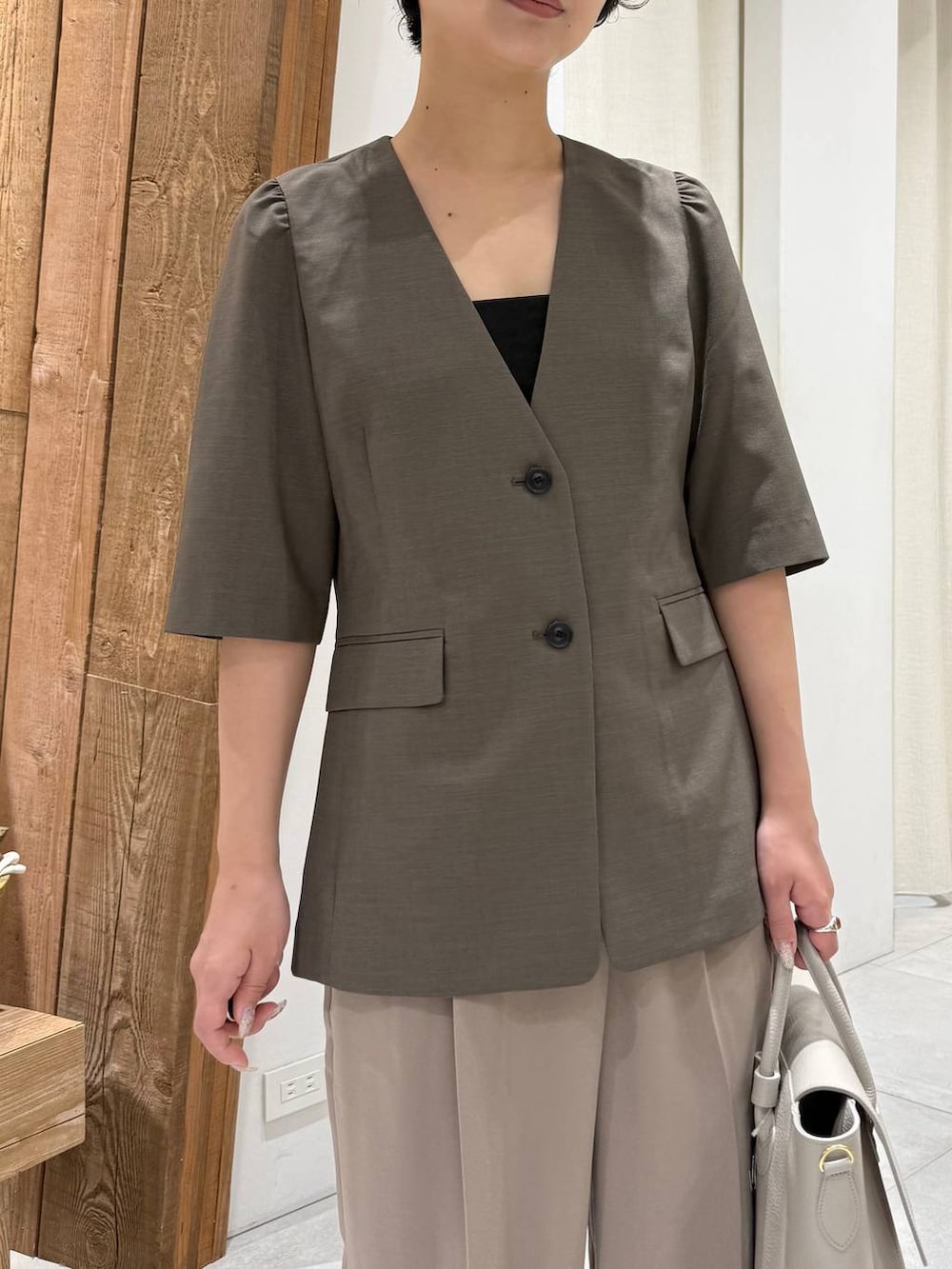 ベージュ系のパンプス、ブラウン系のノーカラージャケット、ベージュ系のスラックスを着用したレディースの春コーディネートの2枚目の写真