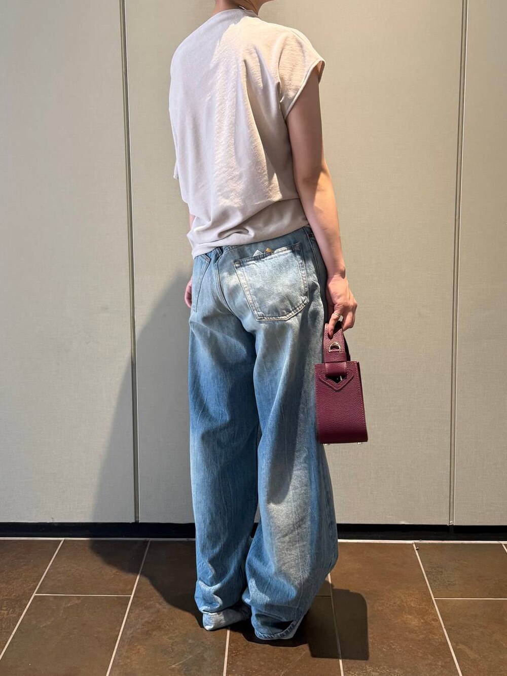 ブラック系のサンダル、ベージュ系のTシャツ/カットソー、ブルー系のデニムパンツを着用したレディースの夏コーディネートの4枚目の写真