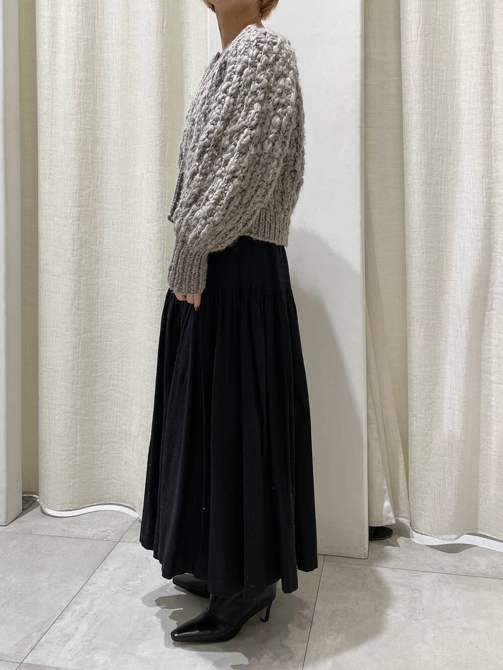 ベージュ系のカーディガン/ボレロ、ブラック系のスカートを着用したレディースの冬コーディネートの3枚目の写真