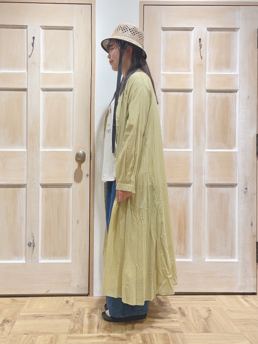 ホワイト系のTシャツ/カットソー、イエロー系のワンピース、ブルー系のデニムパンツを着用したレディースの春コーディネートの2枚目の写真