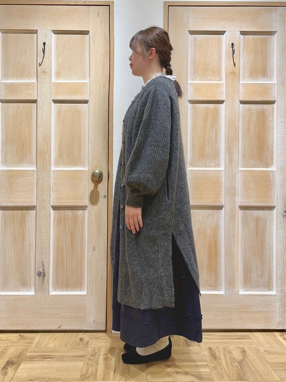 グレー系のカーディガン/ボレロ、グレー系のシャツ/ブラウス、ブラック系のスカートを着用したレディースの冬コーディネートの2枚目の写真