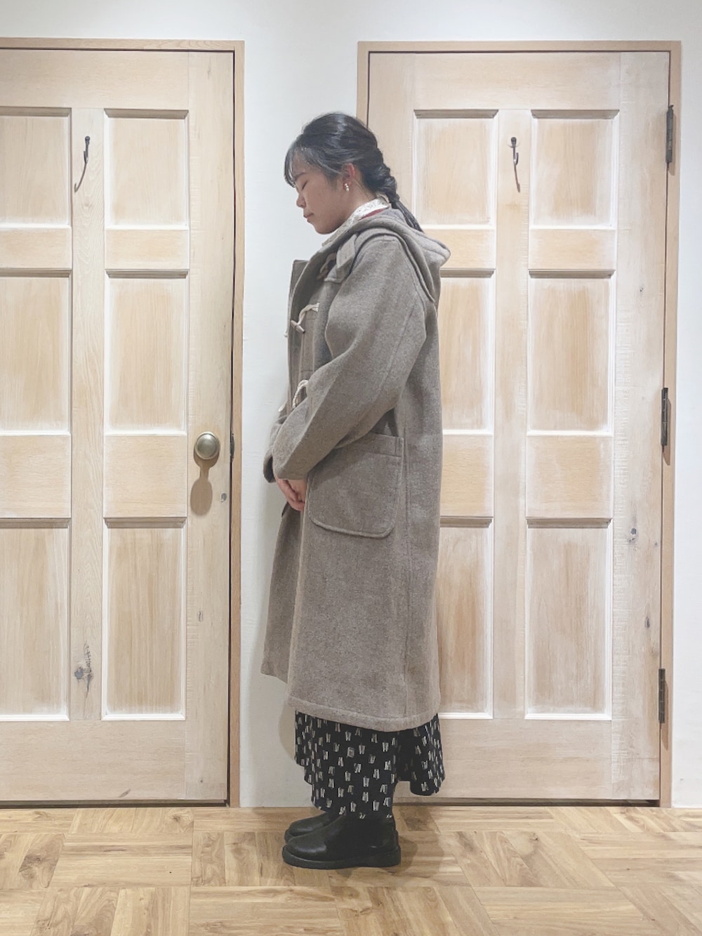 ベージュ系のダッフルコート、ブラック系のスカート、ブラック系のブーツを着用したレディースの秋コーディネートの2枚目の写真