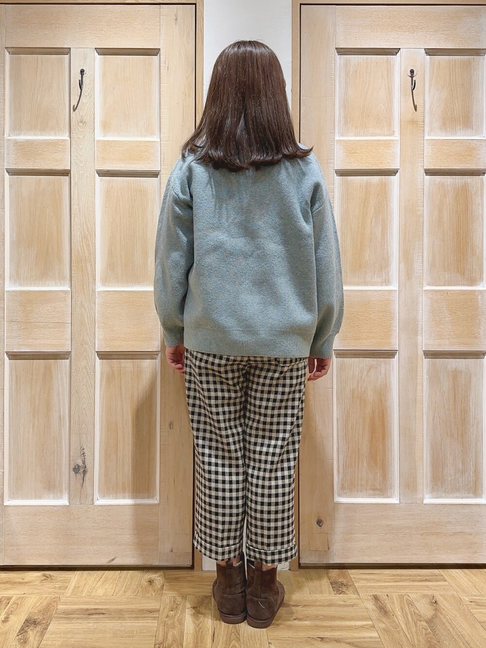 グリーン系のニット/セーター、ベージュ系のその他パンツ、ブラウン系のブーツを着用したレディースの冬コーディネートの3枚目の写真