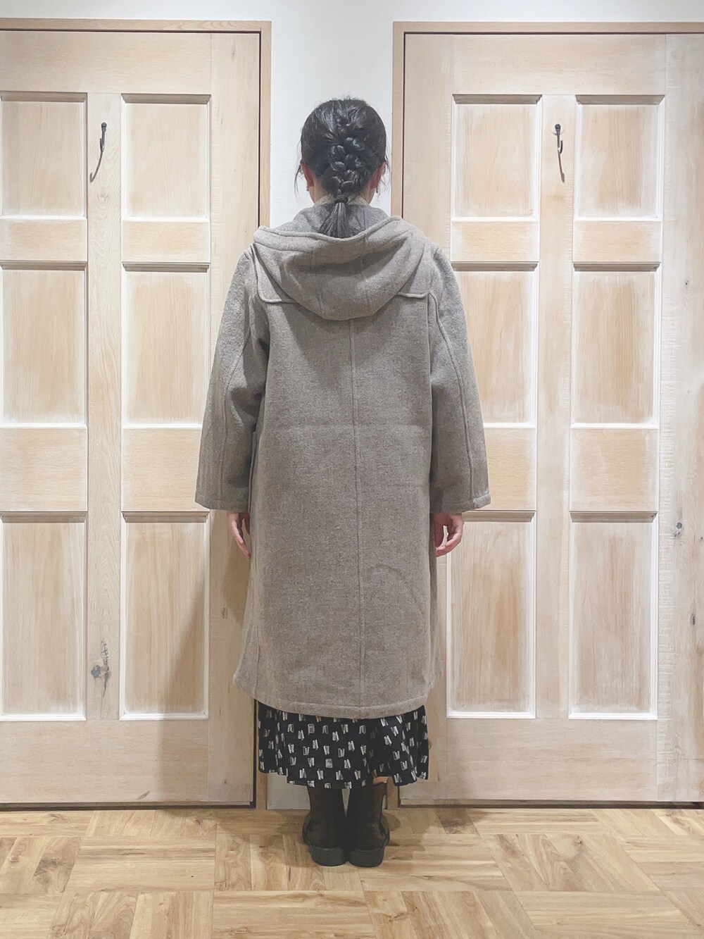 ベージュ系のダッフルコート、ブラック系のスカート、ブラック系のブーツを着用したレディースの秋コーディネートの3枚目の写真