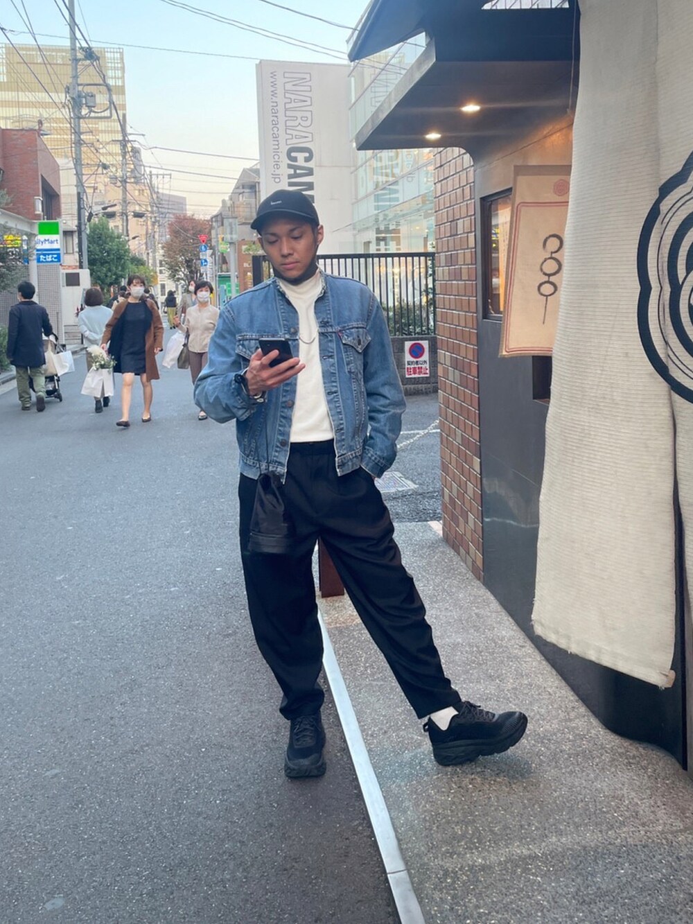 ブルー系のデニムジャケット、ブラック系のスニーカー、ブラック系のパンツを着用したメンズの秋コーディネートの2枚目の写真