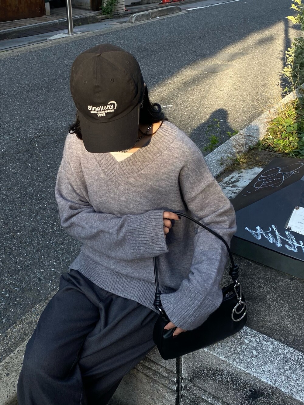 グレー系のニット/セーター、グレー系のスラックス、ブラック系のショルダーバッグを着用したレディースの秋コーディネートの2枚目の写真