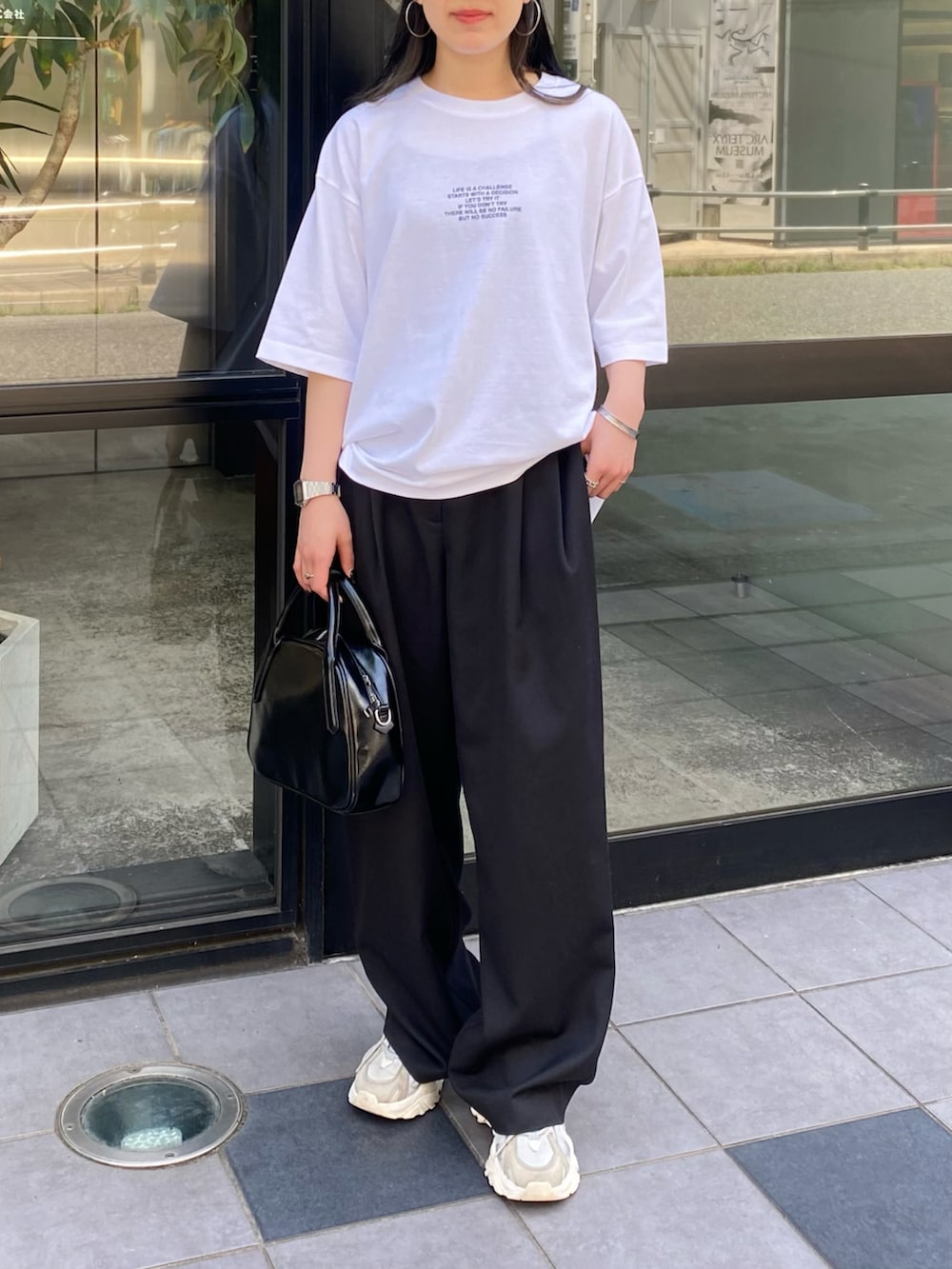 ホワイト系のTシャツ/カットソー、ブラック系のスラックス、ブラック系のボストンバッグを着用したレディースの春コーディネートの4枚目の写真