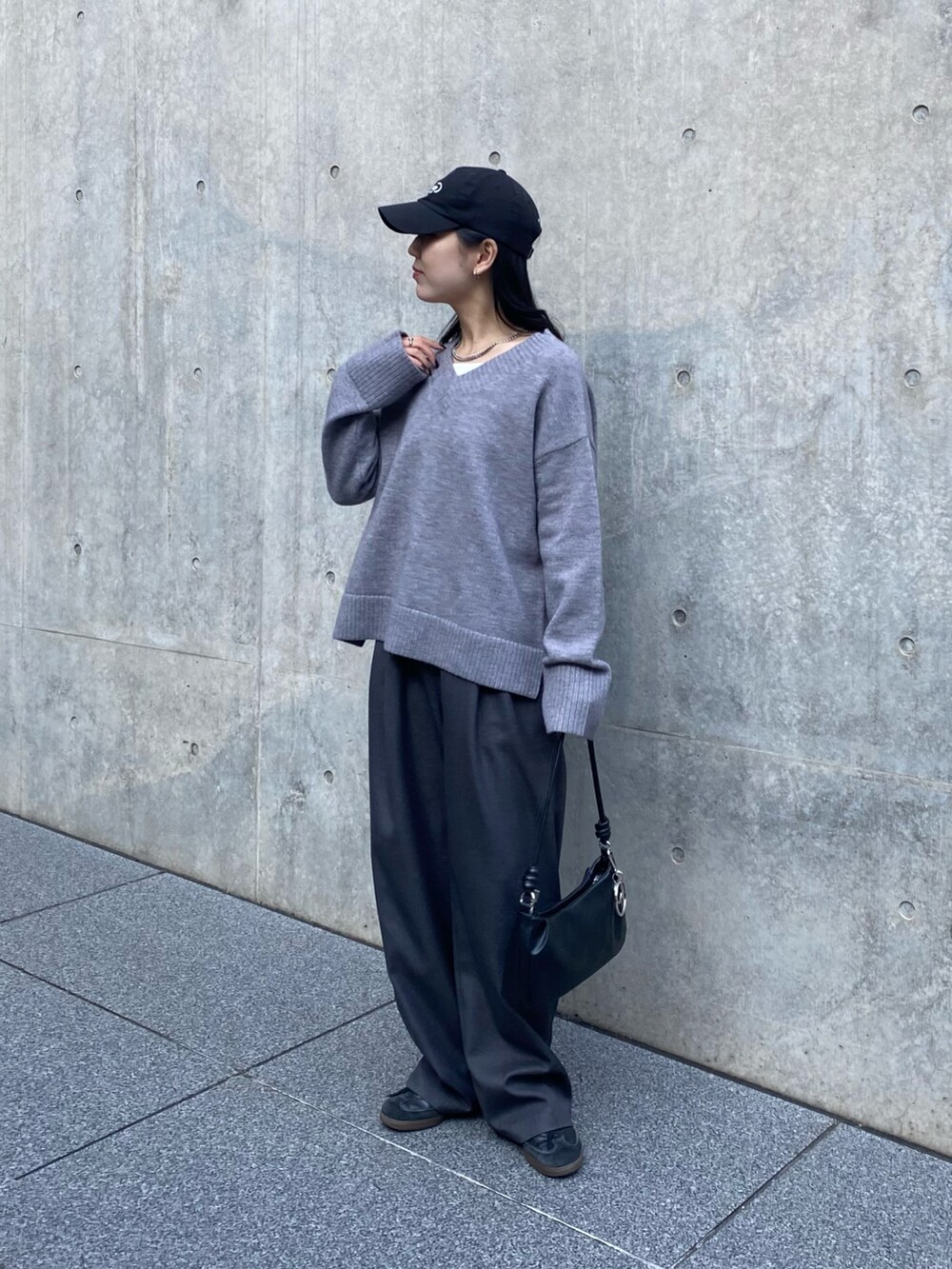 グレー系のニット/セーター、グレー系のスラックス、ブラック系のショルダーバッグを着用したレディースの秋コーディネートの5枚目の写真