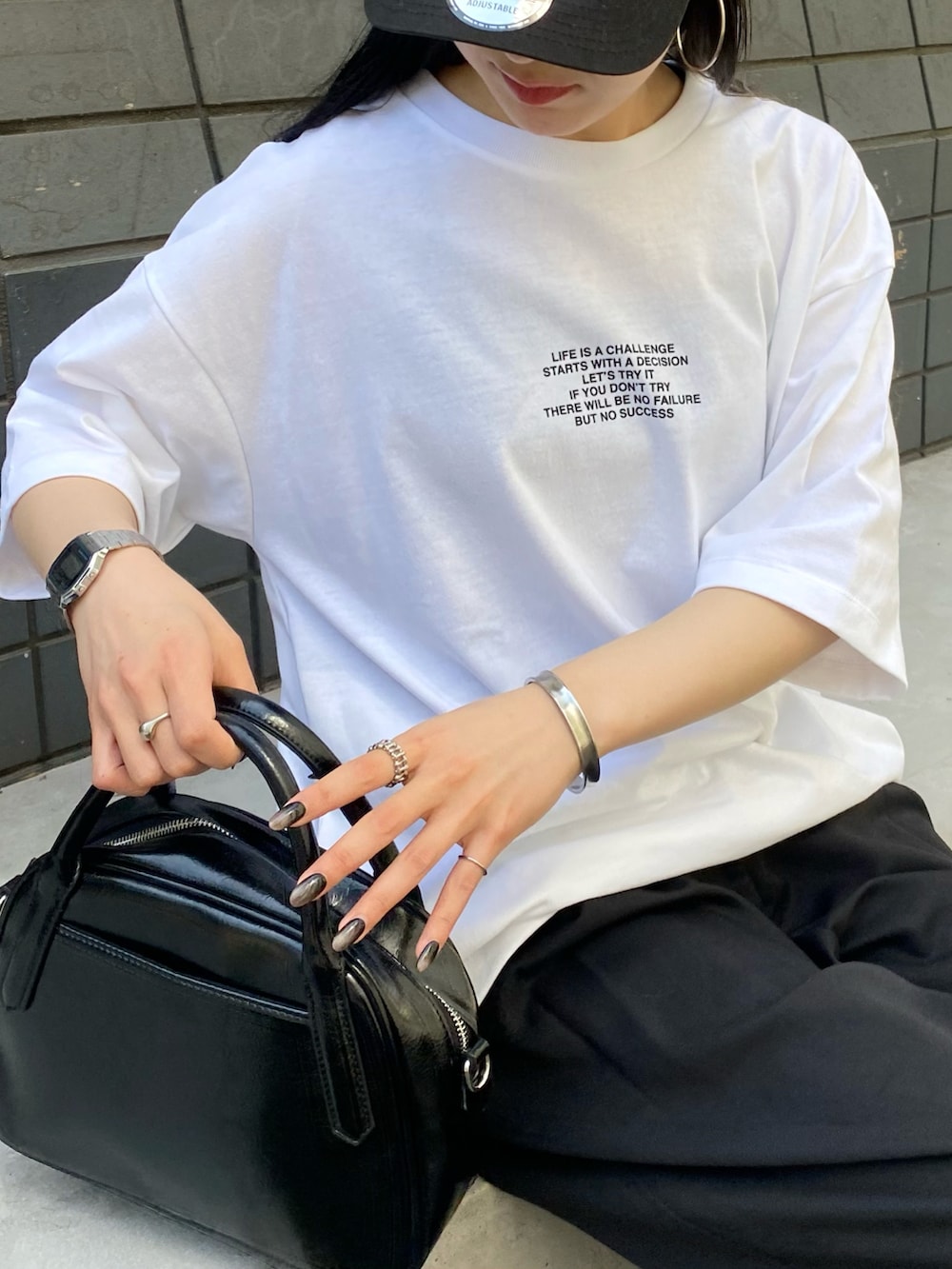 ホワイト系のTシャツ/カットソー、ブラック系のスラックス、ブラック系のボストンバッグを着用したレディースの春コーディネートの2枚目の写真