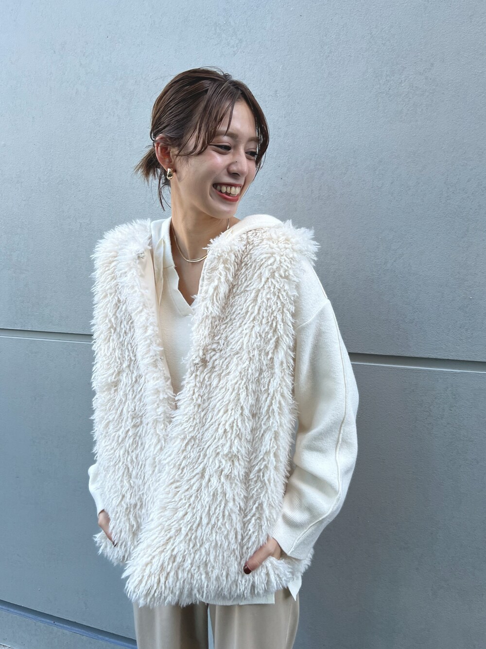 ベージュ系のスウェットパンツ、ホワイト系のパーカー、ホワイト系のベストを着用したレディースの冬コーディネートの2枚目の写真