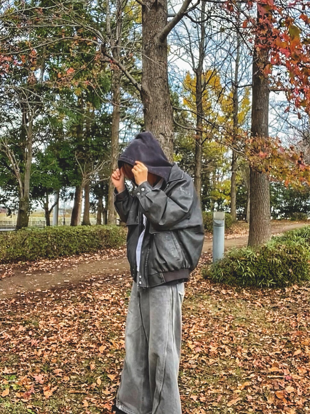 ブラック系のブルゾン、ホワイト系のTシャツ/カットソー、グレー系のデニムパンツを着用したメンズの秋コーディネートの3枚目の写真