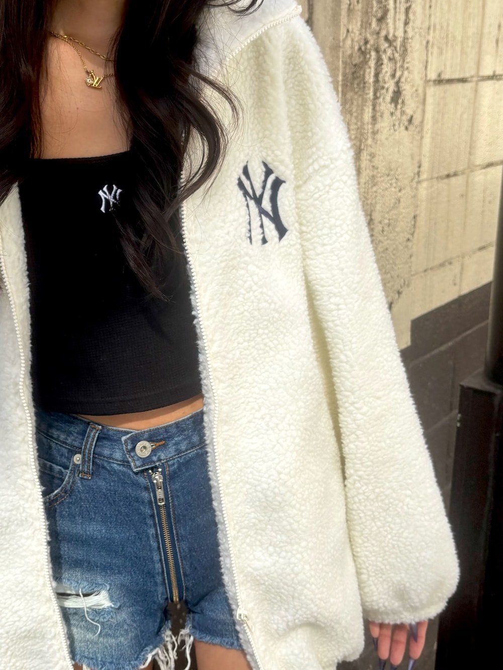 ブラック系のブーツ、ブルー系のデニムパンツ、ホワイト系のブルゾンを着用したレディースの秋コーディネートの4枚目の写真