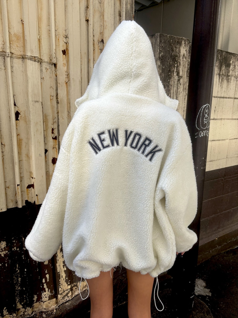 ブラック系のブーツ、ブルー系のデニムパンツ、ホワイト系のブルゾンを着用したレディースの秋コーディネートの3枚目の写真