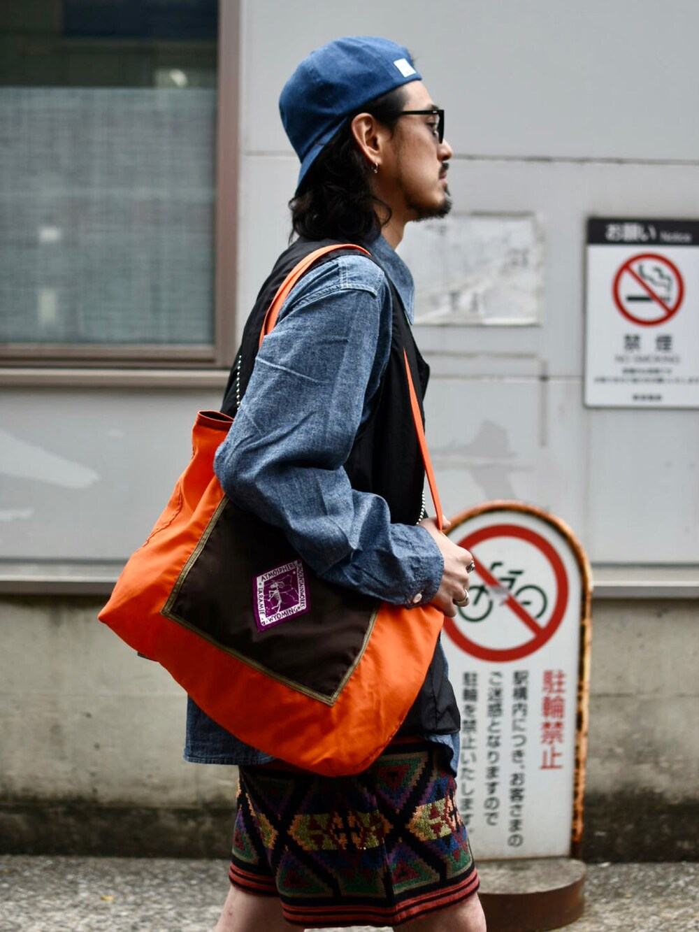 オレンジ系のトートバッグ、ブルー系のシャツ/ブラウス、ブラック系のベストを着用したメンズの春コーディネートの3枚目の写真