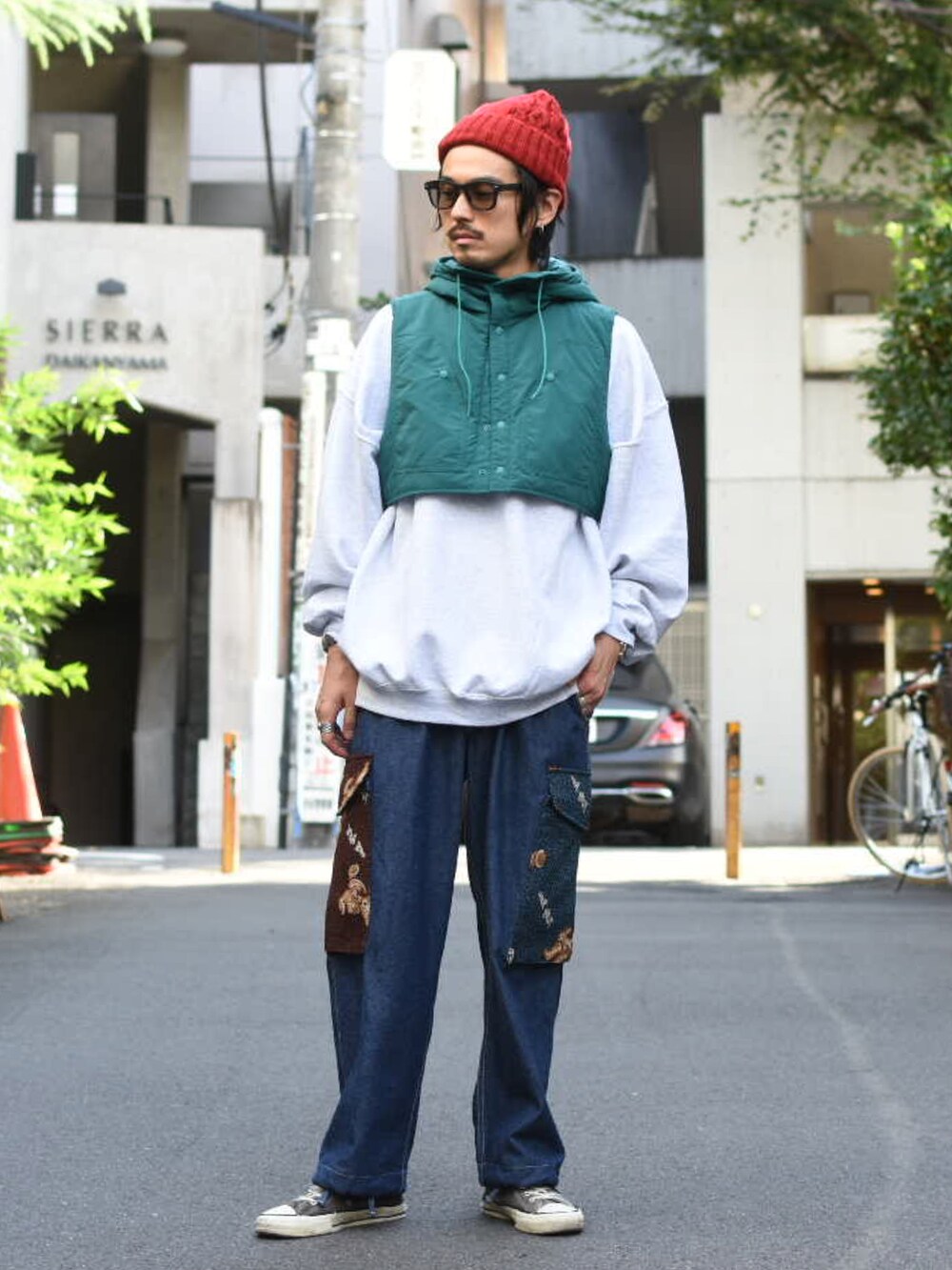 グリーン系のダウンベスト、グレー系のスウェット、ブルー系のパンツを着用したメンズの秋コーディネートの2枚目の写真